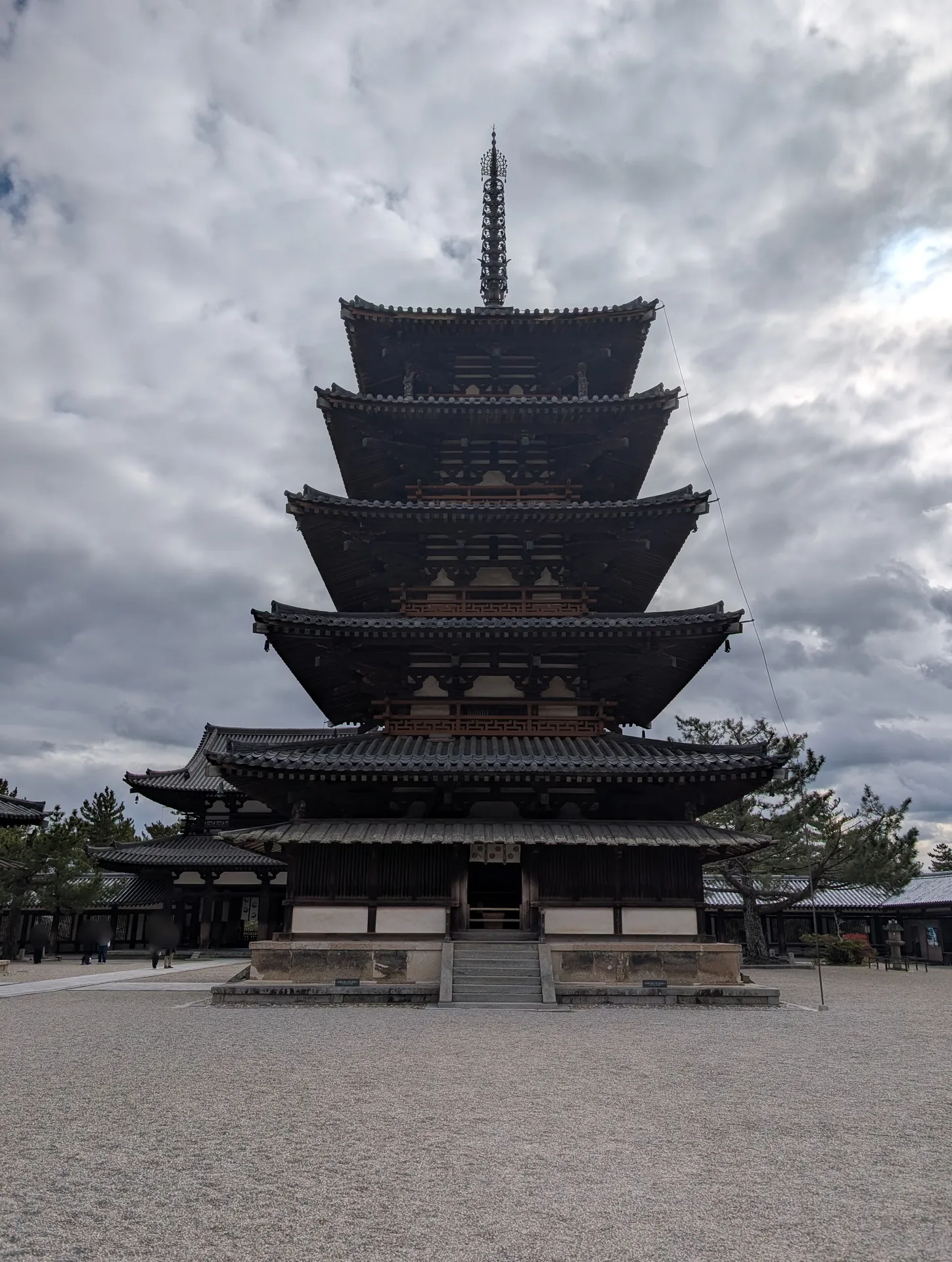 西院の五重塔を正面から見上げた写真。雲の多い冬の空に、5つの屋根が重なる